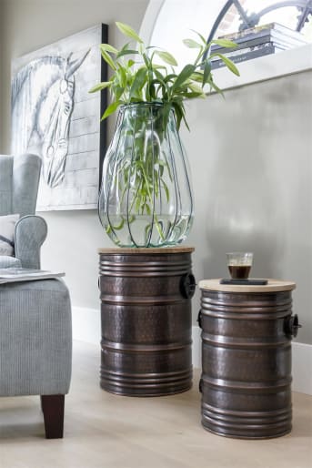 Bijzettafel Barrel van COCO Maison is er in een large en medium uitvoering. De bijzettafel is geïnspireerd op een olievat. Het blad van is van exotisch hout wat mooi past bij de warme bronskleur van de tafel.